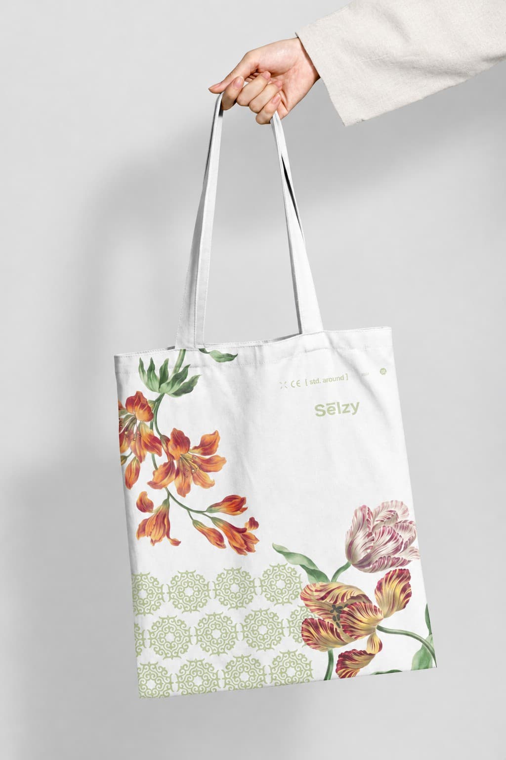 Selzy tote bag with a floral print, held up in studio light